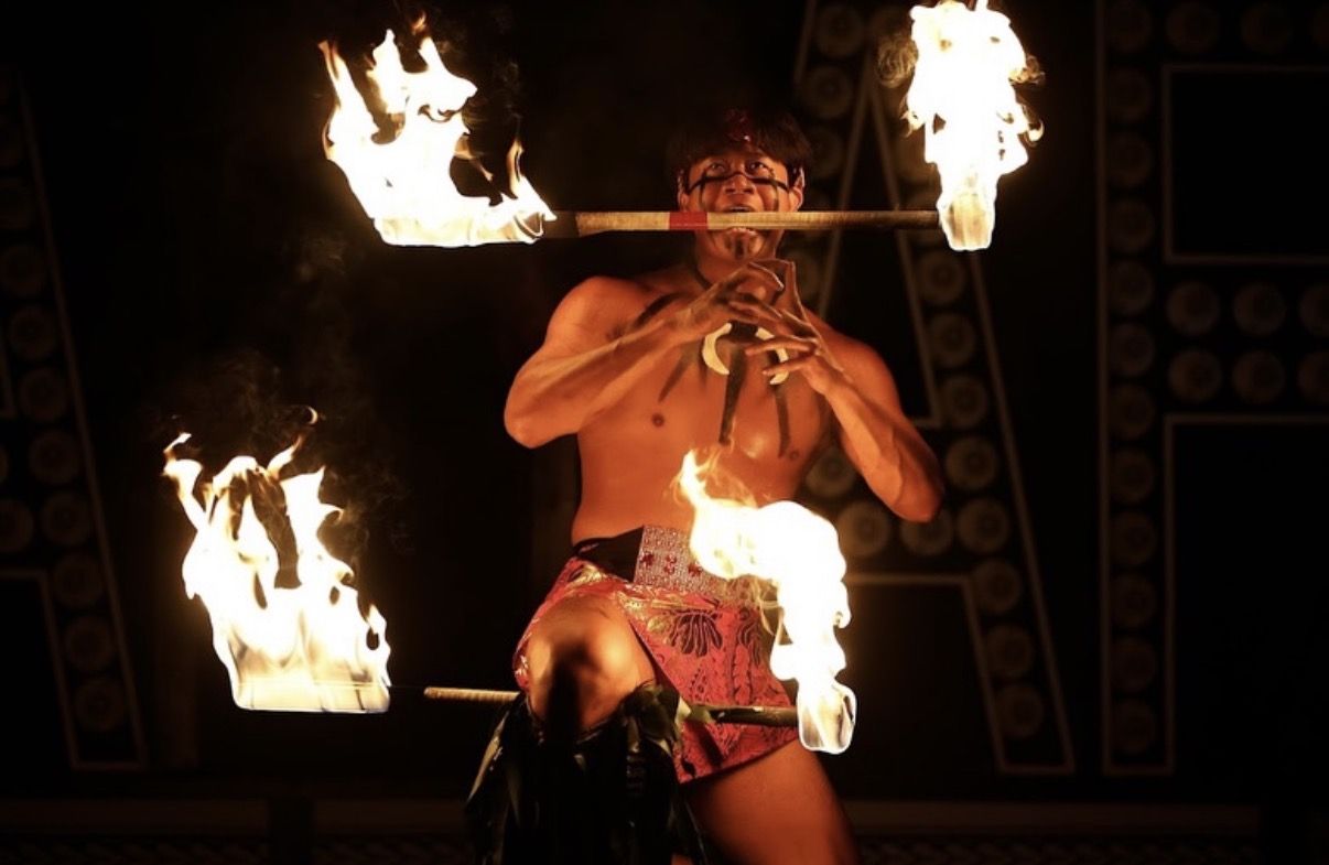 Fire dancer holding a flaming staff in his teeth