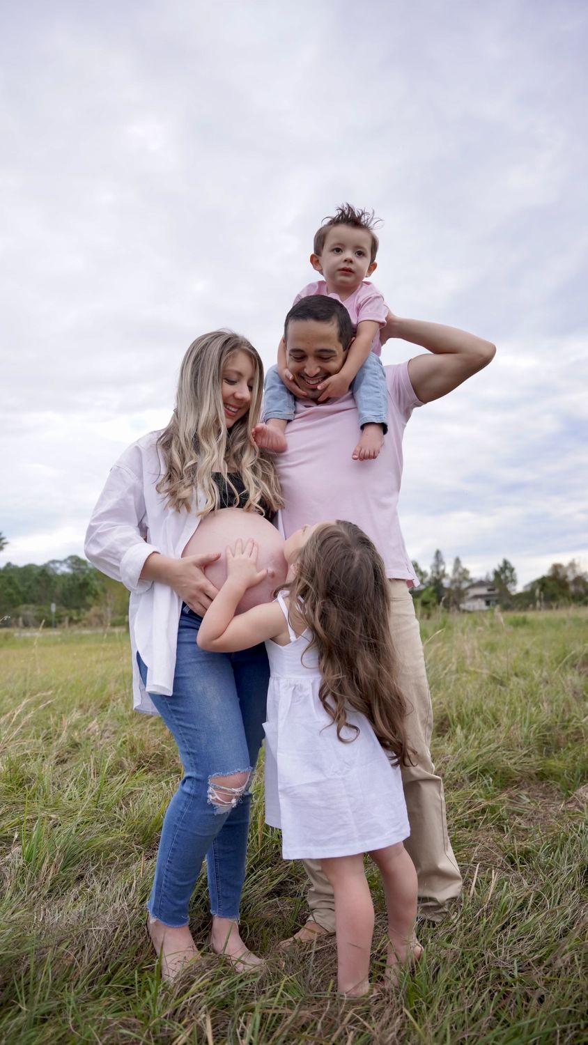 Daughter kissing her mother's belly while dad holds their son