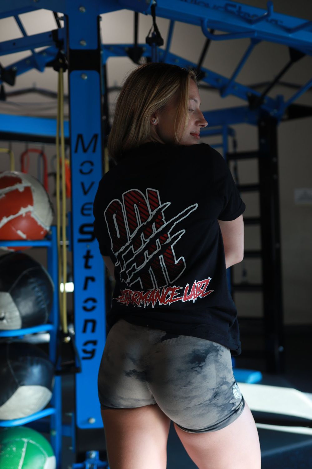 Athlete showing the back print of a black graphic tee in a gym