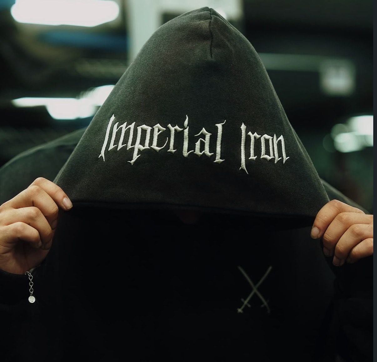Model holding an Imperial Iron embroidered hood over his face