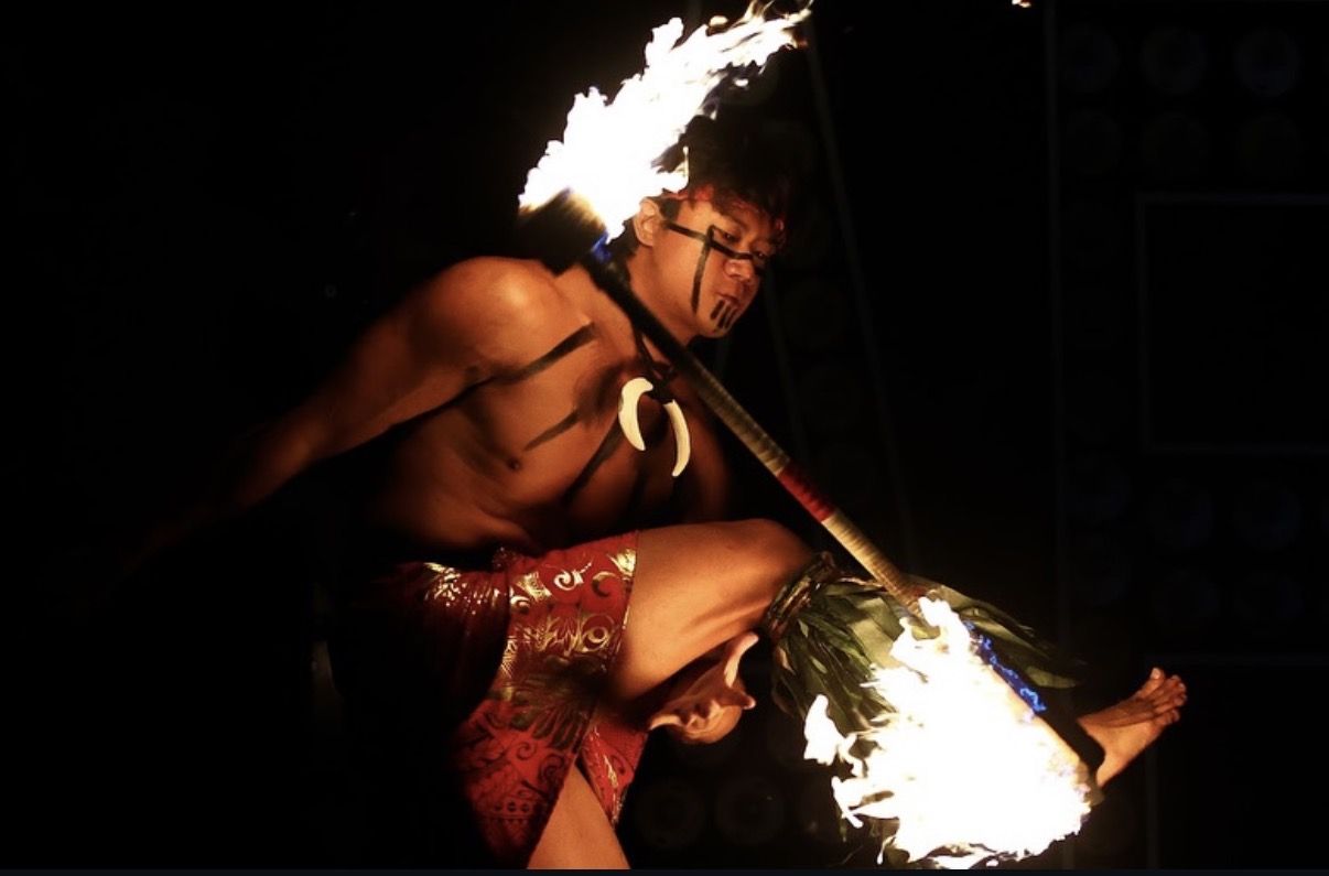 Fire dancer mid kick with a burning staff