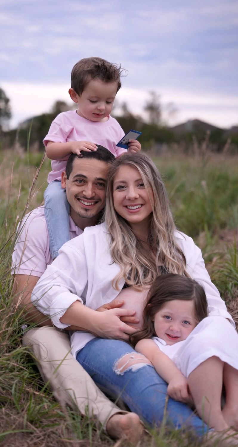 Family maternity portrait sitting together in tall grass